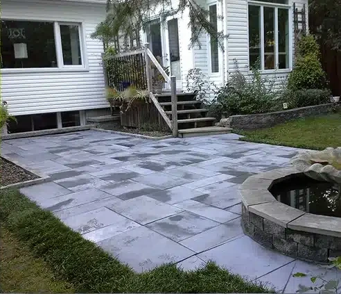 Overgrown backyard rebuilt with a natural stone patio — after
