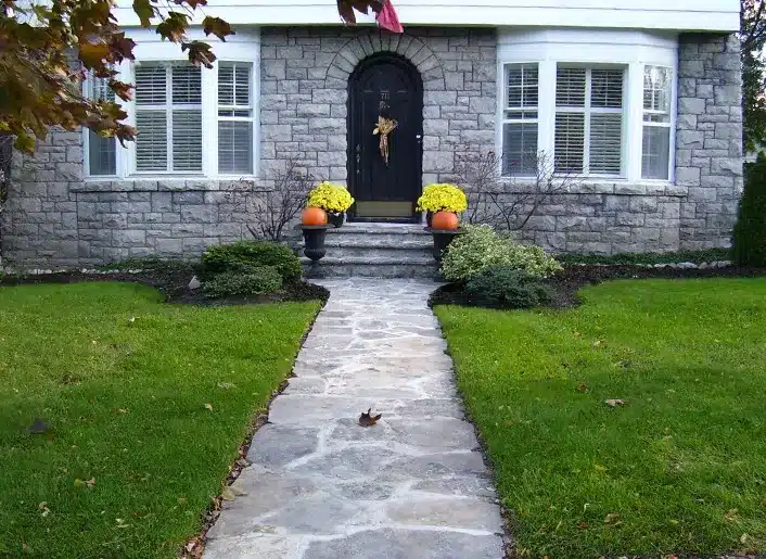 Stone patio and walkway leading through a landscaped yard